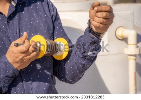 man holding spool charkhi of string with glass covering showing fighting kites flown on sankranti uttarayan independence day in Delhi