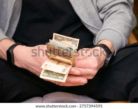 Man holding stack of mixed currency banknotes. Counting money in hand for financial transaction. Payment, investment, savings and budget concept. Economic wealth and business success.