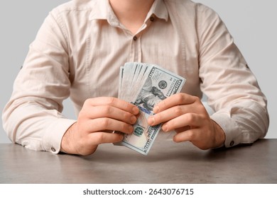 Man holding stack of one hundred dollar bills, financial management and wealth accumulation