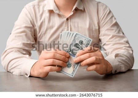 Man holding stack of one hundred dollar bills, financial management and wealth accumulation