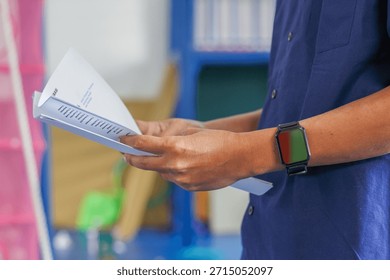 Man Holding a Stack of Paper Documents in a Classroom Setting