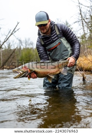 man holding steelhead michigan river rainbow trout