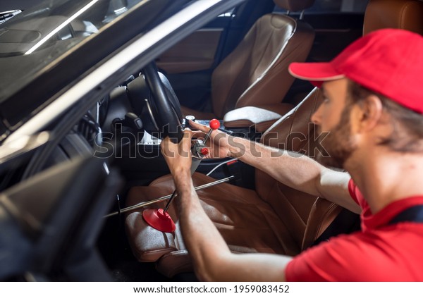Man holding\
steering wheel crouched near\
car