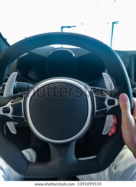 man holding steering wheel in luxury car.\
Steering wheel of luxury sport\
car.