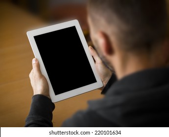 Man Holding A Tablet With Blank Screen. Perspective From Behind The Arm