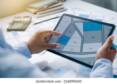 Man holding a tablet looking at lots of lands. Land plot management - real estate concept with vacant land for building construction and housing subdivision for sale, rent, buy, or investment