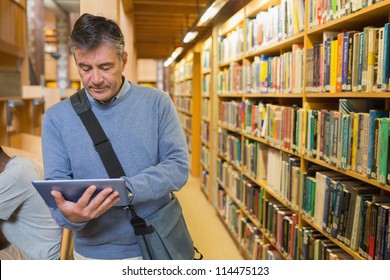 Man holding a tablet pc amongst shelves in a library