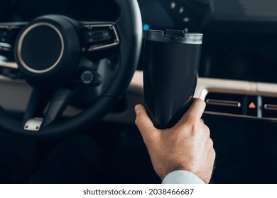 A man holding a thermo mug while driving an expensive car
 - Powered by Shutterstock