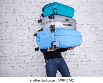 Man holding three heavy suitcases in hand. Travel light.