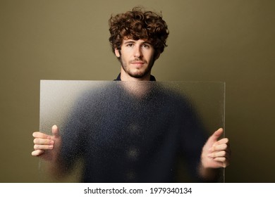 Man holding a translucent glass by the wall - Shutterstock ID 1979340134