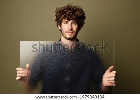Man holding a translucent glass by the wall