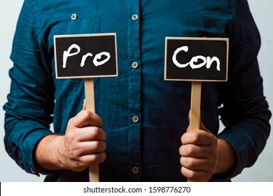 Man Holding Two Chalkboards With Pro And Con