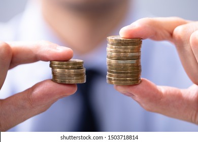 Man Holding Two Coin Stacks To Compare - Shutterstock ID 1503718814