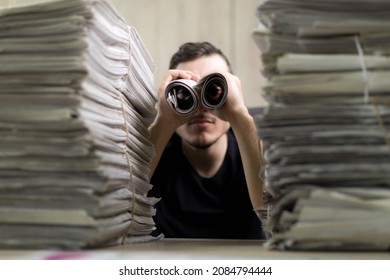 Man holding two twisted roll newspaper. Metaphor or allegory with binoculars. Selective focus on newspapers. Truth search concept