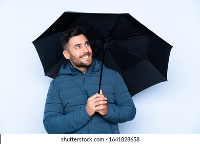 Man holding an umbrella over isolated background with happy expression - Powered by Shutterstock