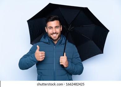 Man holding an umbrella over isolated background with thumbs up because something good has happened - Powered by Shutterstock