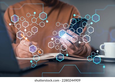 Man holding, using smartphone typing at office workplace with notebook. Concept of distant work, business education. Blockchain crypto hologram. Shot of hands.