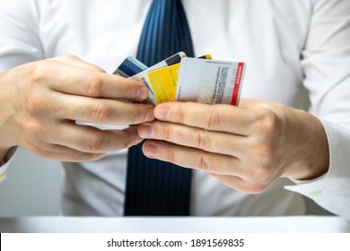 Man Holding Various Credit Cards In His Hand In Front Of A White Background. Credit Card Usage. Conscious Consumers. Consumer Shopping Habits.