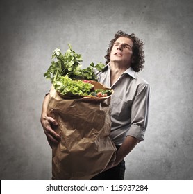 Man Holding A Very Heavy Bag Full Of Vegetables