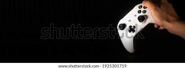 Man holding video\
game control with black background. Banner for video games and\
games with space for text.
