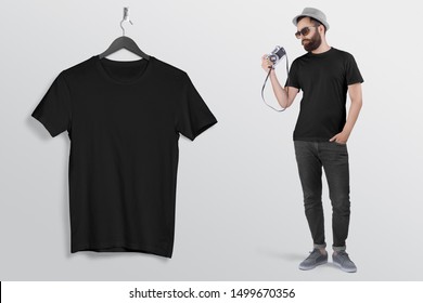 Man Holding Vintage Camera In Black Crew Neck T Shirt Hand In Pocket Wearing Back Denim Jeans Pant Hanging T Shirt On Hanger