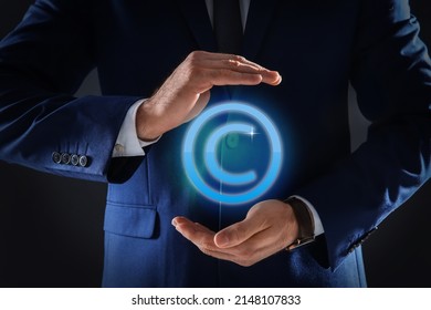 Man Holding Virtual Icon Of Copyright Symbol On Dark Background, Closeup