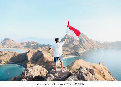 A man holding and waving Indonesian flag on top mountain at Labuan Bajo Indonesia - Shutterstock ID 2025107837