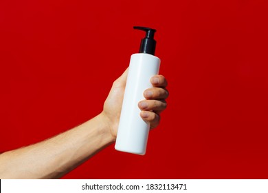 Man Holding A White Bottle Isolated On Red Background.Man Hand Holding A Bottle (on Red Background)