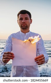 Man Holding White Burning Paper At The Background Of The Sea.