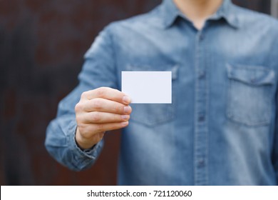 Man Holding White Business Card On Wall Background