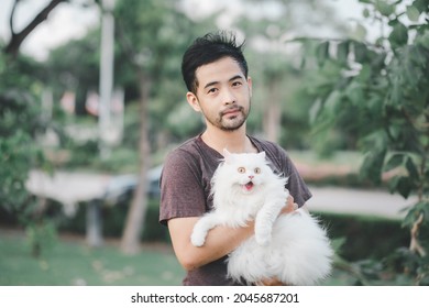 Man Holding A White Cat In A Park. Excited Cat