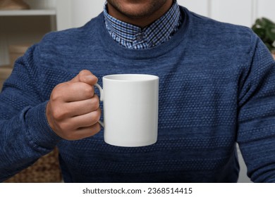 Man holding white mug indoors, closeup. Mockup for design - Powered by Shutterstock