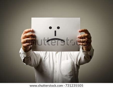 Man is holding white paper with smile. Unhappy and trouble concept.
