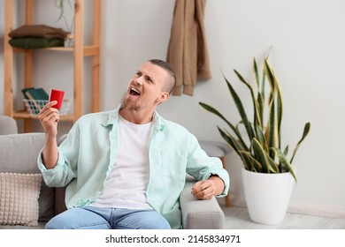 Man Holding Wireless Portable Speaker And Singing On Sofa