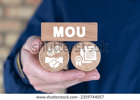 Man holding wooden blocks with abbreviation: MOU. Business concept of Memorandum Of Understanding (MOU). MOU Memorandum Of Understanding - type of agreement between two or more parties.