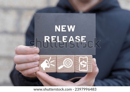 Man holding wooden cubes with icons and black sticky note with inscription: NEW RELEASE. New release concept. New product development. Update software version.