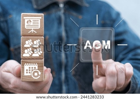 Man holding wooden cubes with icons presses virtual button with abbreviation: AGM. Annual General Meeting of shareholders. AGM Annual General Meeting Business Corporate Management Concept.