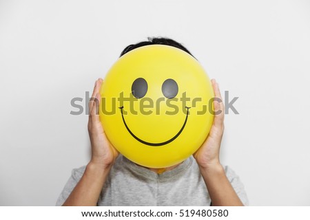 A man holding yellow balloon with smile face emotion instead of head. Positive Thinking concepts. hiding some bad feeling just keep smiling 商業照片 © 