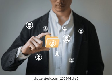 A man is holding a yellow folder with a bunch of people on it. The people are all connected to the folder - Powered by Shutterstock