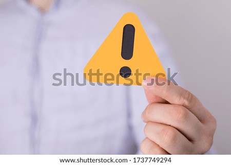 A man holding a yellow triangular warning sign