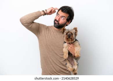 Man holding a yorkshire isolated on white background having doubts and with confuse face expression