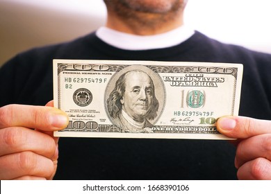 Man Holds A 100 Dollar Bill In His Hand