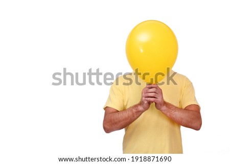 A man holds a balloon covering his face. Yellow ball covering the face. The male covers his face with a yellow balloon. Unwillingness to communicate with people. Isolated on a white background. People