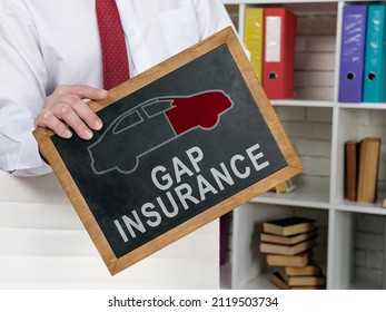 Man holds blackboard with Gap insurance words on it.