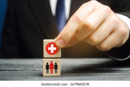 A man holds a block with a medical cross and people. Healthcare, medicine and charity concept. Health insurance. Ambulance. Coronavirus pandemic infection COVID-19.