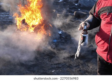 Man holds bottle with Molotov cocktail next to barricades on the Hrushevsky street during anti-government Euromaidan protest on January 2014 in Kyiv, Ukraine - Shutterstock ID 2270556983