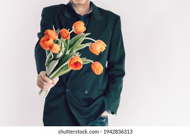 A Man Holds A Bouquet Of Flowers In Front Of Him. Bright Orange Tulips As A Gift For Birthday, Valentine's Day, Mother's Day, International Women's Day. Flowers In Men's Hands. Selective Focus.