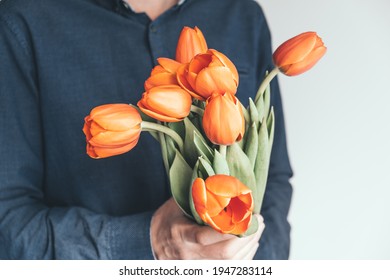 A Man Holds A Bouquet Of Flowers In Front Of Him. Bright Orange Tulips As A Gift For Birthday, Valentine's Day, Mother's Day, International Women's Day. Flowers In Men's Hands.