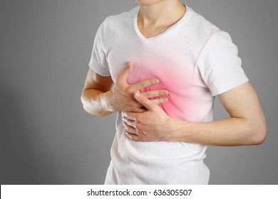 A Man Holds The Breasts. The Pain In His Chest. Heartburn. Stomach Hurts. Sore Point Highlighted In Red. Closeup. Isolated.