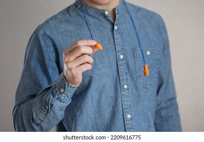 Man Holds Bright Earplugs. Closeup.